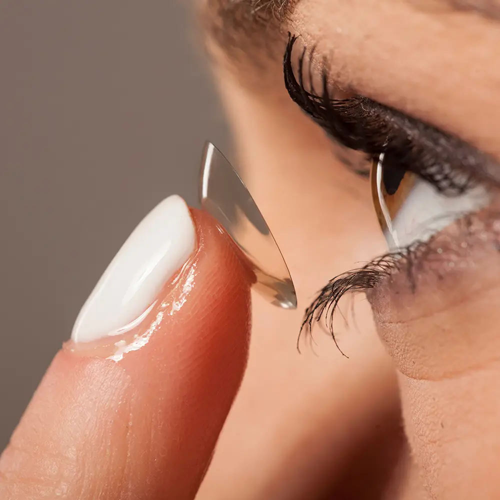 Close-up of a person carefully placing a contact lens onto the eye